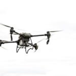 Een commerciële drone vliegt hoog boven een stedelijk landschap voor inspectie- en surveillancedoeleinden.